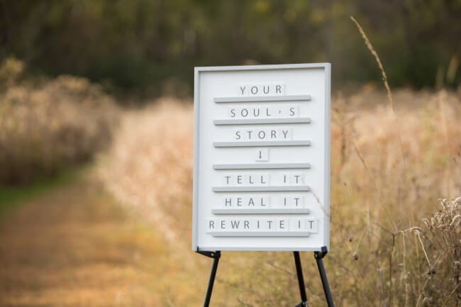 Picture of Your Soul's Story Sign In front of a field and path.